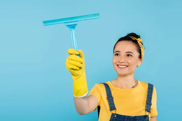 穿着黄色橡胶手套的高兴女人拿着窗户清洁剂隔离在蓝色中 — 图库照片