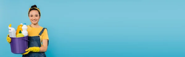 Mavi Pankartta Izole Edilmiş Temizleyicilerle Dolu Kovayı Tutarken Kameraya Bakan — Stok fotoğraf