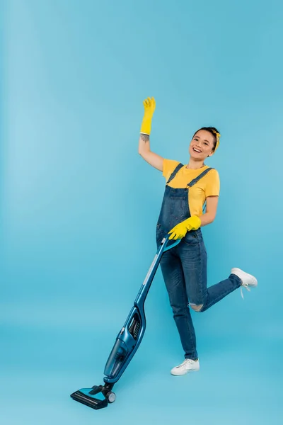 Cheerful Woman Denim Clothes Rubber Gloves Waving Hand While Vacuuming — Stock Photo, Image