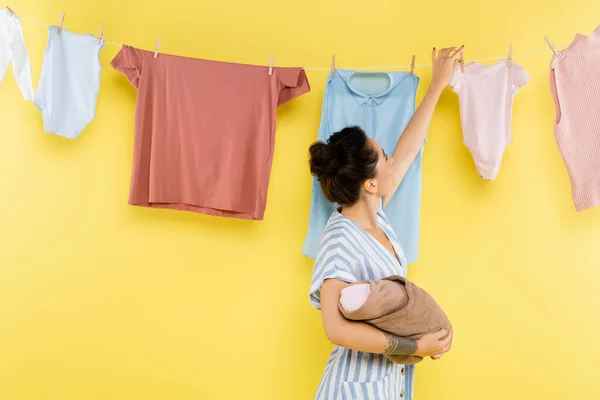 Brunette Woman Hanging Clothing Rope While Holding Baby Doll Yellow — Stock Photo, Image