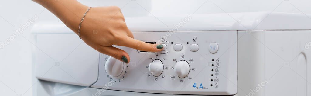partial view of woman pushing button on washing machine, banner 