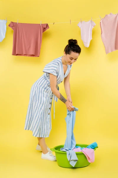 Full Length View Woman Taking Clothes Laundry Bowl Yellow Background — Stock Photo, Image