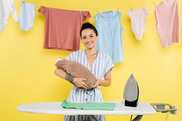 Mujer Alegre Mirando Cámara Mientras Sostiene Muñeca Cerca Tabla Planchar —  Fotos de Stock