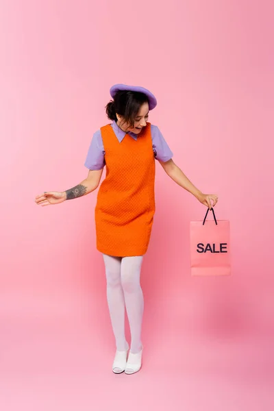 ピンクの販売レタリングでショッピングバッグを見て驚きの女性の完全な長さビュー — ストック写真
