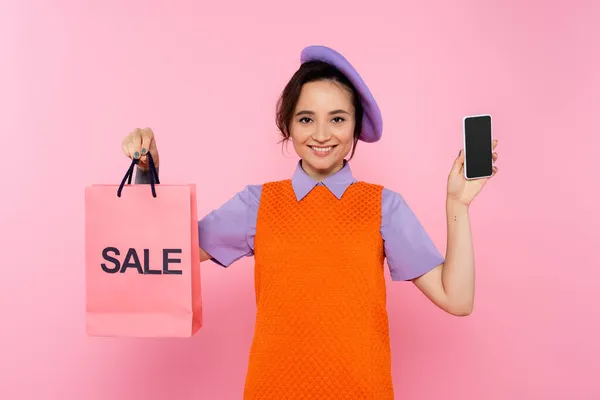 Vrolijke Vrouw Oranje Mouwloze Jurk Tonen Smartphone Verkoop Boodschappentas Geïsoleerd — Stockfoto