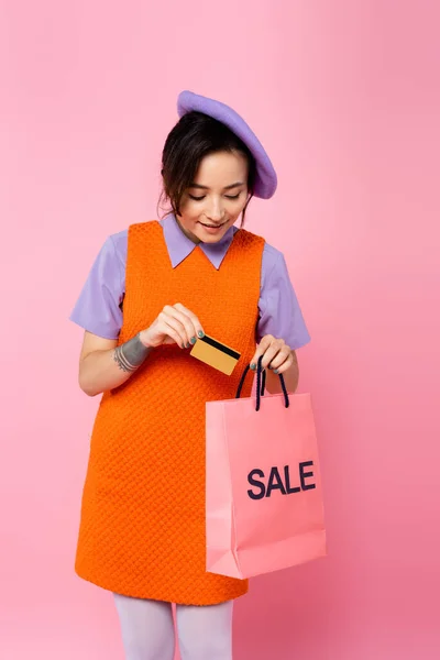 年轻女子把信用卡放进购物袋里 购物袋上贴上粉红色的便条 — 图库照片