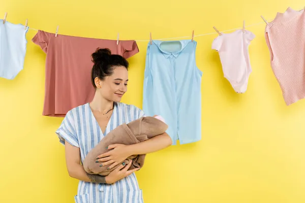 Mujer Alegre Sosteniendo Muñeca Cerca Ropa Colgando Cuerda Fondo Amarillo —  Fotos de Stock