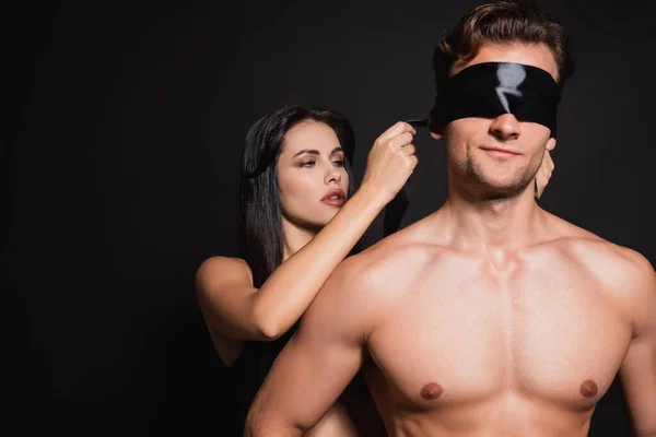 Brunette Woman Tying Blindfold Shirtless Man Isolated Black — Stock Photo, Image