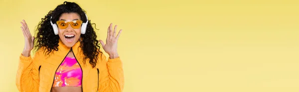 Здивована Афроамериканська Молода Жінка Сонцезахисних Окулярах Навушниках Ізольована Жовтому Банер — стокове фото