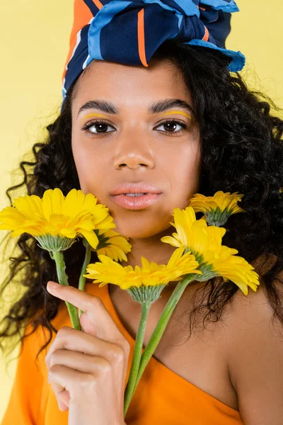 Αφροαμερικανή Νεαρή Γυναίκα Που Κρατάει Λουλούδια Απομονωμένα Στο Κίτρινο — Φωτογραφία Αρχείου
