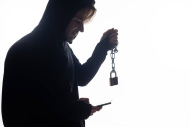 Akıllı telefon kullanan ve beyaz üzerinde asma kilit tutan hackerın yan görünümü 