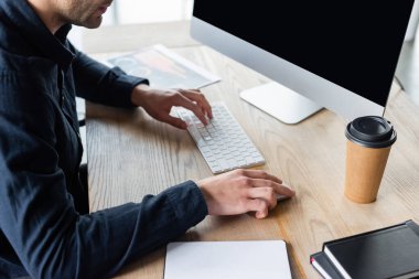Ofiste kağıt bardak ve defterlerin yanında bilgisayar kullanan programcı görüntüsü 