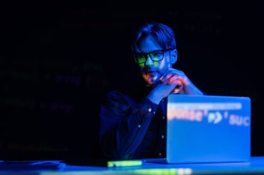 Ofiste kod yansıması siyah üzerine izole edilmiş gözlüklü geliştirici bilgisayarın yanında oturuyor 