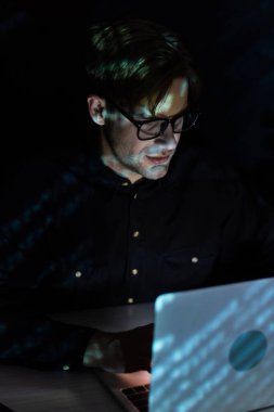 Siyah ekranda izole edilmiş dizüstü bilgisayar kullanan gözlüklü programcı 