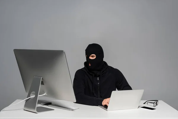 Hacker Passamontagna Utilizzando Computer Laptop Vicino Smartphone Sul Tavolo Isolato — Foto Stock