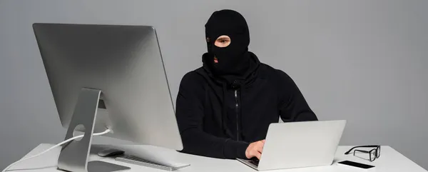 Hacker Passamontagna Utilizzando Laptop Vicino Computer Smartphone Isolato Grigio Banner — Foto Stock