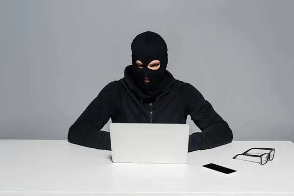 Hacker Bivakmuts Met Laptop Buurt Van Smartphone Bril Tafel Geïsoleerd — Stockfoto