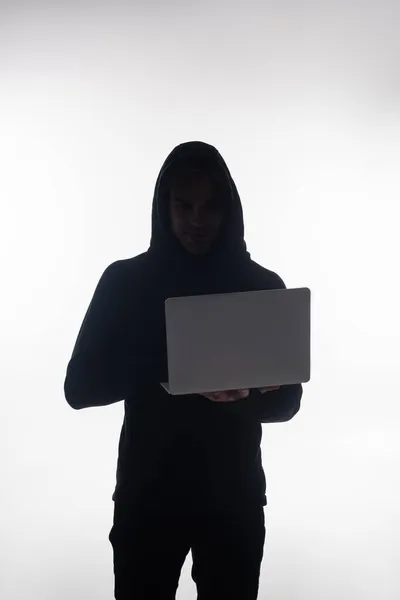 Haker Trzyma Laptopa Patrzy Kamerę Odizolowaną Szaro — Zdjęcie stockowe