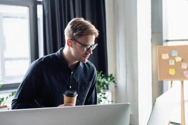 컴퓨터 모니터 근처에서 커피를 이어폰을 사용하는 프로그래머 — 스톡 사진