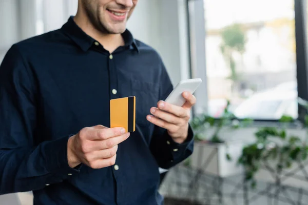 Vista Cortada Programador Desfocado Segurando Cartão Crédito Smartphone Escritório — Fotografia de Stock