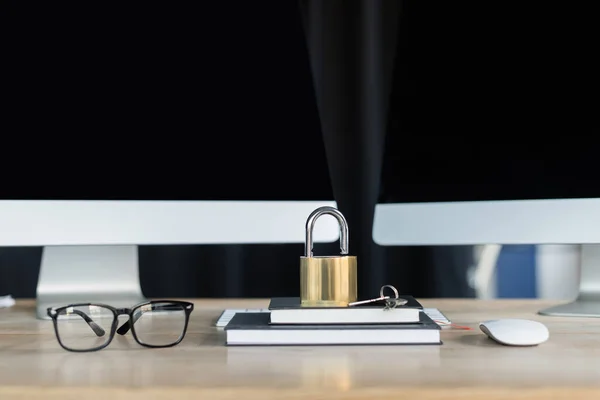 眼镜旁边的笔记本和办公室桌上的计算机上的挂锁 — 图库照片