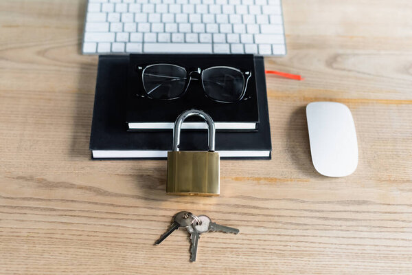 High angle view of padlock with keys near notebooks and computers mouse in office 