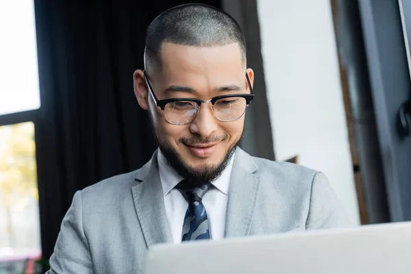 Feliz Asiático Hombre Negocios Gafas Usando Borrosa Laptop Oficina —  Fotos de Stock