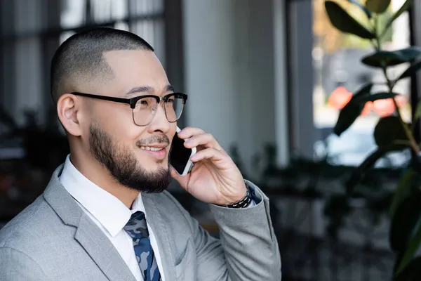 Asiático Empresário Óculos Falando Celular Sorrindo Escritório — Fotografia de Stock