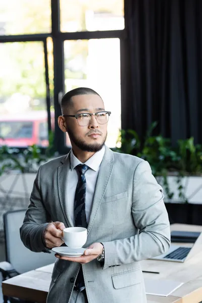 Asiático Empresário Segurando Xícara Café Olhando Para Longe Escritório — Fotografia de Stock