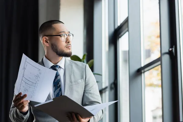 Asian Architect Eyeglasses Looking Away While Holding Folder Blueprints — Stock Photo, Image