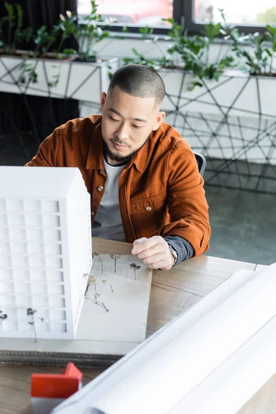 Asiatischer Ingenieur Arbeitet Der Nähe Von Verschwommenen Hausmodellen Und Papieren — Stockfoto