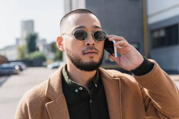 Trendy Asian Man Coat Sunglasses Calling Mobile Phone Outdoors — Stok Foto