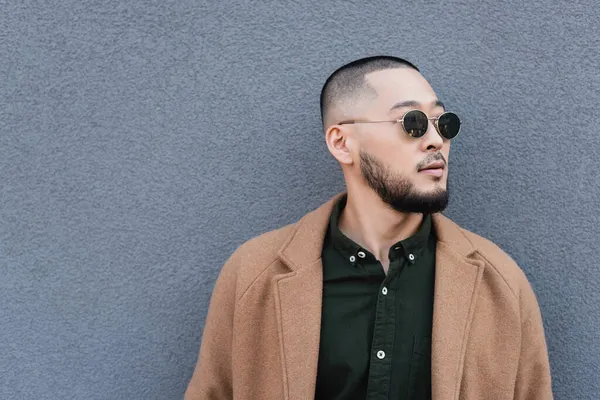 Asian Man Beige Coat Sunglasses Looking Away Grey Wall — Stock Photo, Image