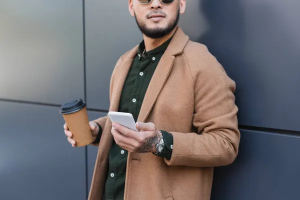 Przycięty Widok Człowieka Beżowym Płaszczu Stojącego Kawą Wynos Smartfona Pobliżu — Zdjęcie stockowe
