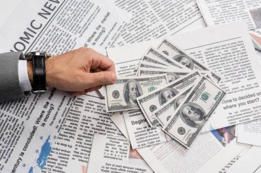 KYIV, UKRAINE - Kasım 1, 2021: basılmış gazetelerin yanında dolar banknotları tutan adamın görüntüsü 