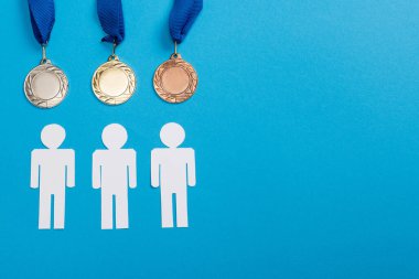 top view of white paper cut people near silver and golden medals on blue clipart