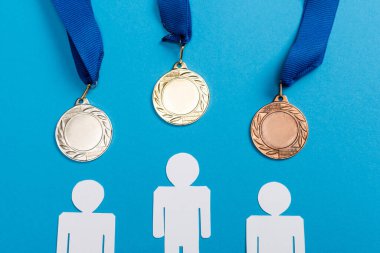 top view of white paper cut people near medals on blue clipart