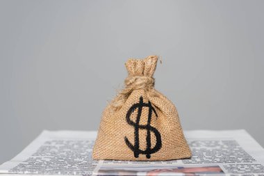 money bag with dollar sign on newspaper isolated on grey clipart