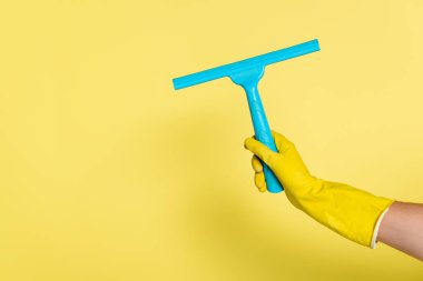 Kırpılmış plastik eldivenli temizleyici manzarası sarıda cam sileceği tutuyor.