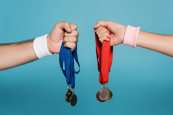 Обрезанный вид мужчины и женщины, держащих медали на голубом фоне