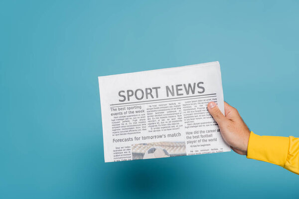 cropped view of man holding newspaper with sport news on blue