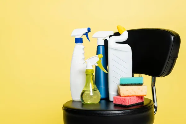 Garrafas Com Detergente Esponjas Limpas Cadeira Preta Isolada Amarelo — Fotografia de Stock