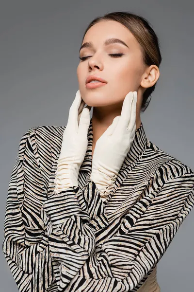 trendy woman in blouse with animal print and gloves posing isolated on grey