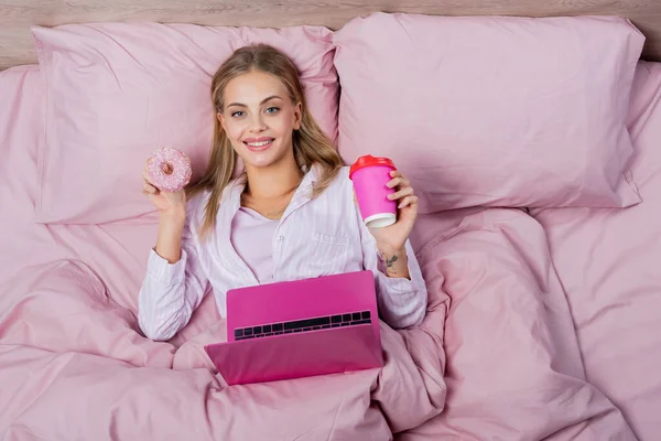 Top View Cheerful Woman Pajamas Holding Paper Cup Donut Laptop — Stock Photo, Image