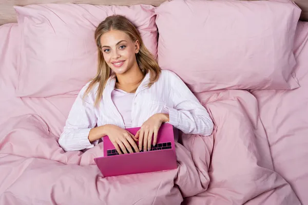 Κάτοψη Της Χαρούμενης Γυναίκας Στην Πιτζάμα Χρησιμοποιώντας Laptop Ροζ Κρεβάτι — Φωτογραφία Αρχείου