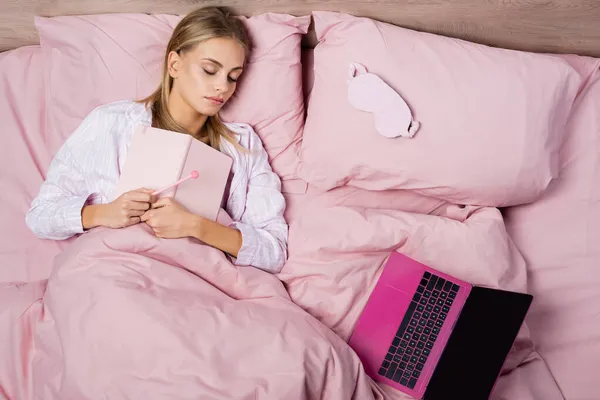 Tampilan Utama Perempuan Memegang Notebook Dekat Laptop Ketika Tidur Tempat — Stok Foto