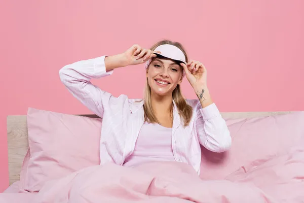 Mulher Loira Feliz Segurando Máscara Sono Cama Isolada Rosa — Fotografia de Stock