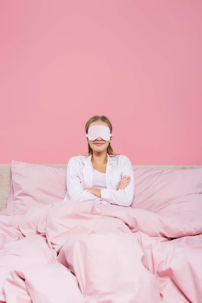 Glimlachende Vrouw Slaap Masker Zitten Met Gekruiste Armen Bed Geïsoleerd — Stockfoto