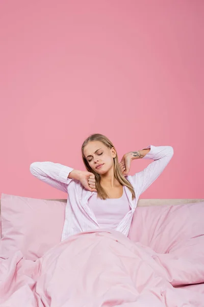 Jong Blond Vrouw Pyjama Stretching Bed Geïsoleerd Roze — Stockfoto