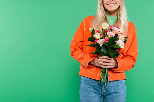 穿着橙色夹克和牛仔裤 手持绿色花朵的微笑女子的剪影 — 图库照片